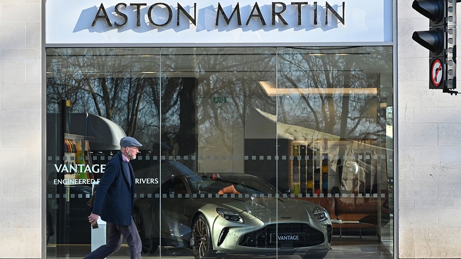 A man walking outside an Aston Martin dealership