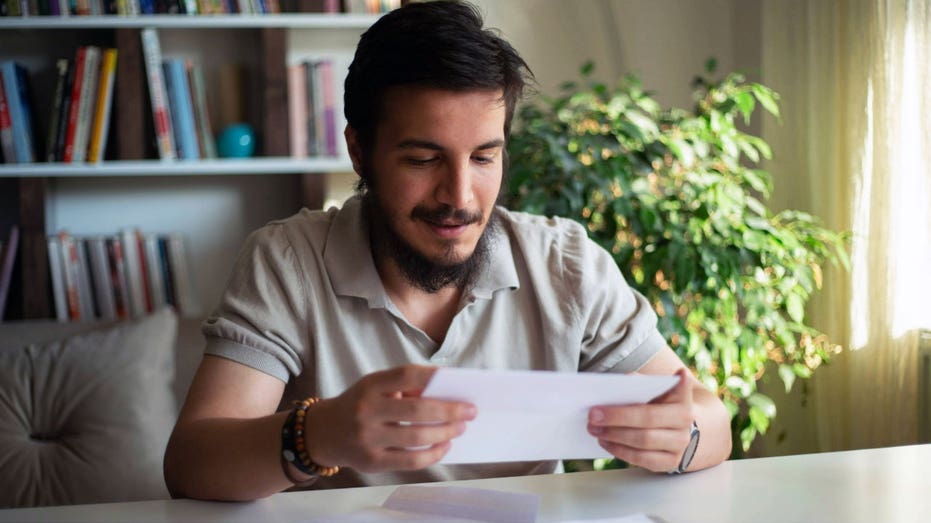 A man sits inside and looks at a piece of paper.