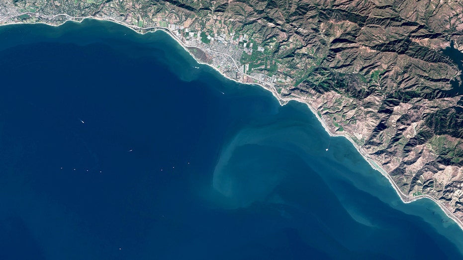 Satellite image of multiple offshore oil platforms and an artificial drilling island in the Santa Barbara Channel near the California coastline.